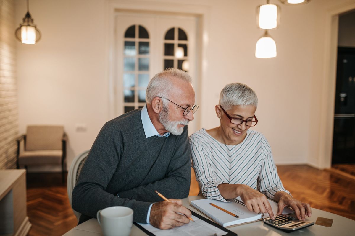 Retirement Planning Services | A happy senior couple calculating their finances in a beautiful home.